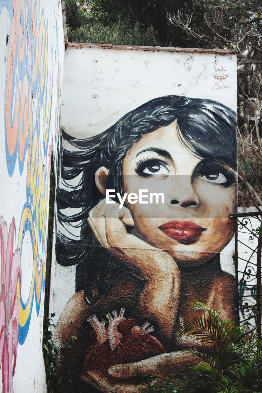 PORTRAIT OF WOMAN WITH GRAFFITI ON WALL