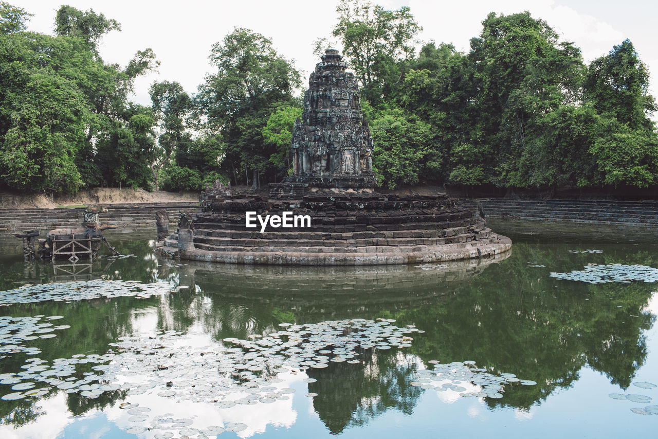 Reflection of stone structure in pond against trees