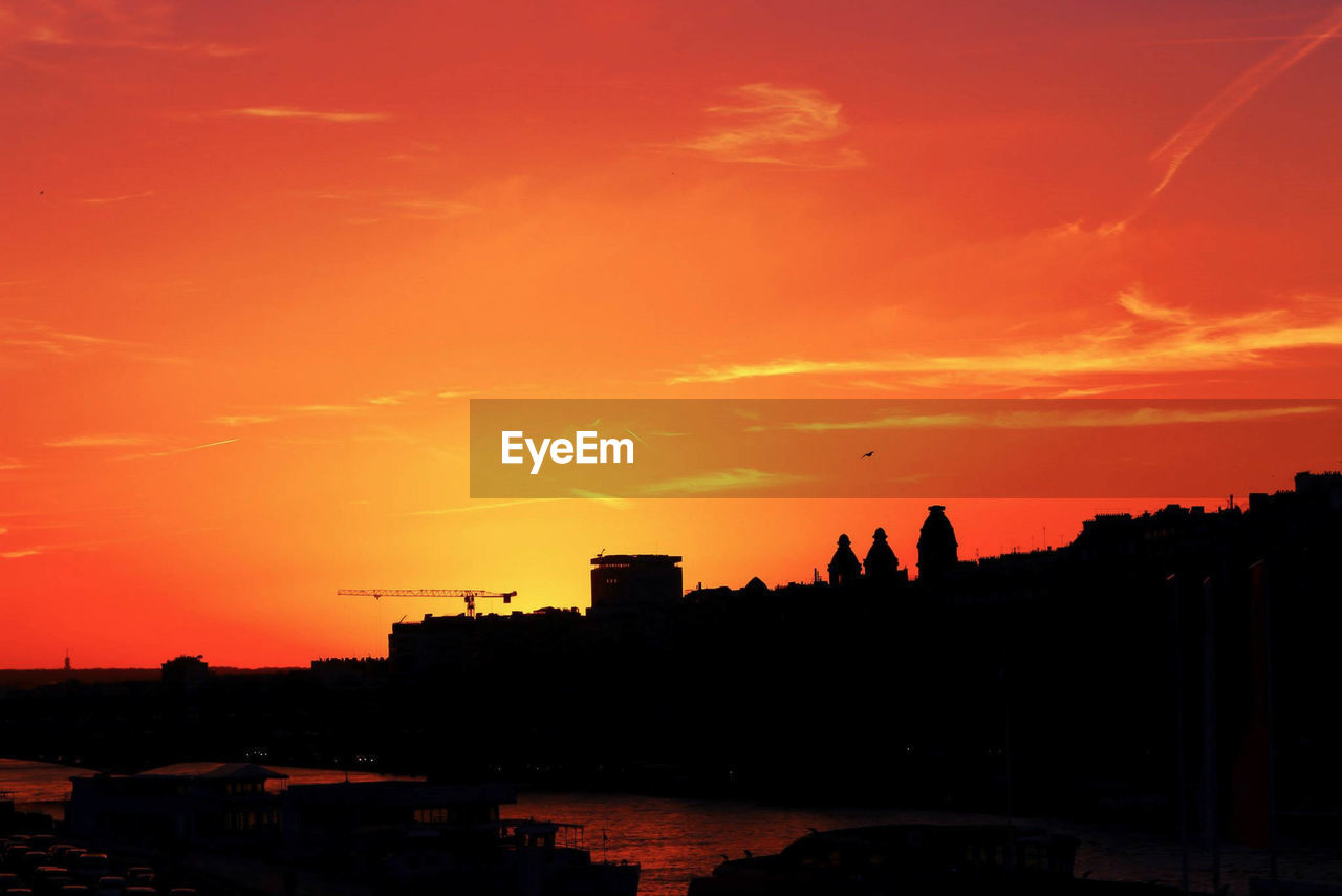 SILHOUETTE BUILDINGS AGAINST ORANGE SKY DURING SUNSET