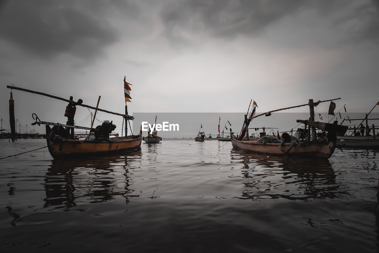 Fishing boats in sea against sky