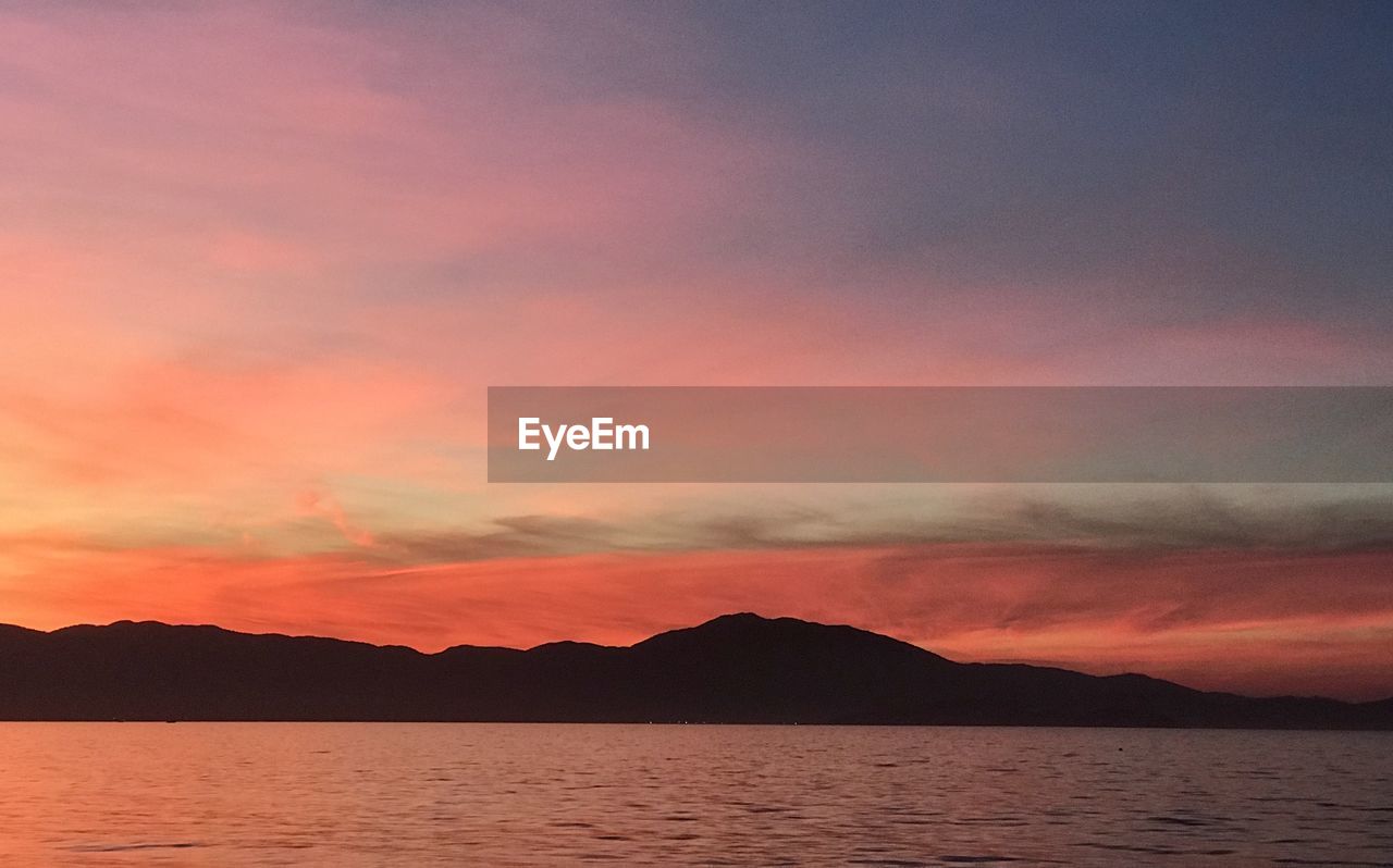 Scenic view of sea against dramatic sky during sunset