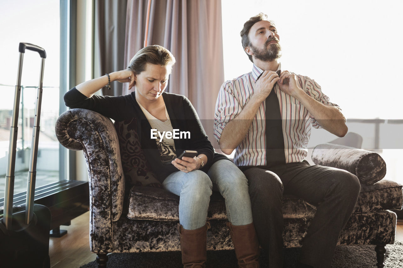 Business couple relaxing on chaise longue in hotel room