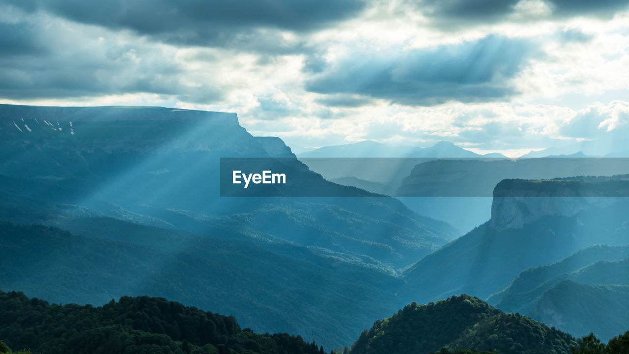 The rays of the setting sun break through the clouds and flow beautifully down the mountain slopes