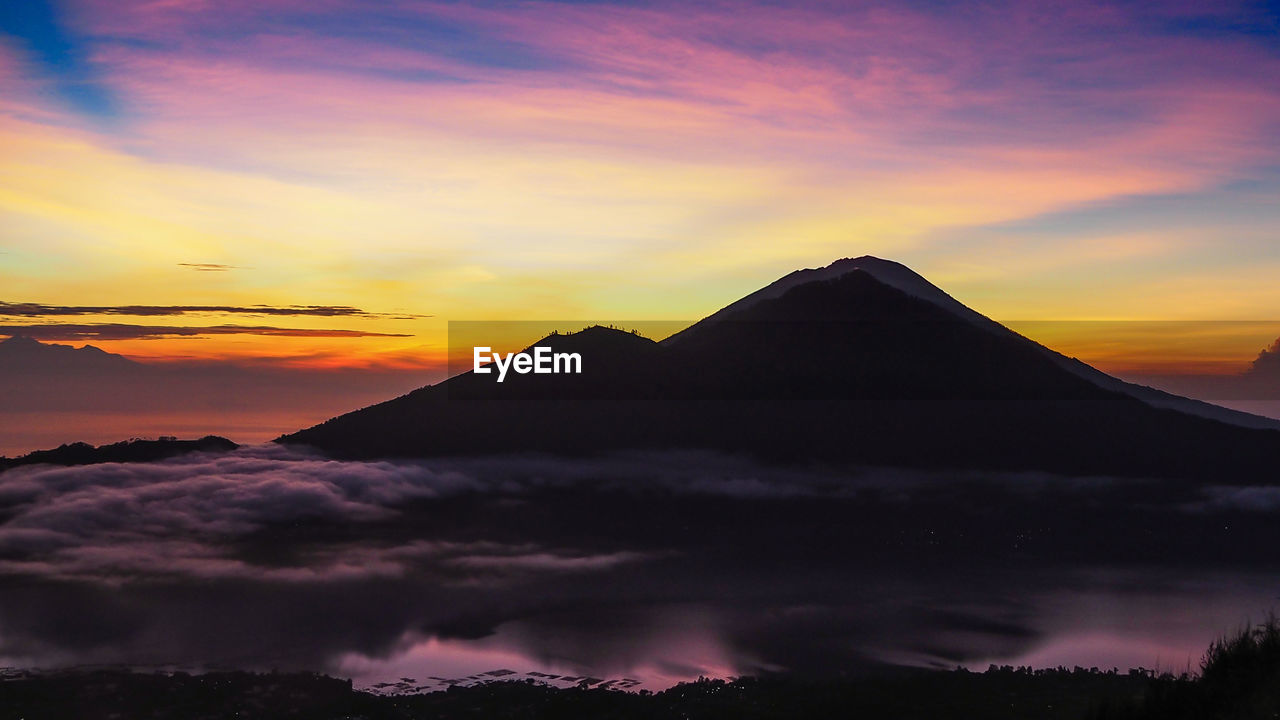 Scenic view of silhouette mountains against orange sky