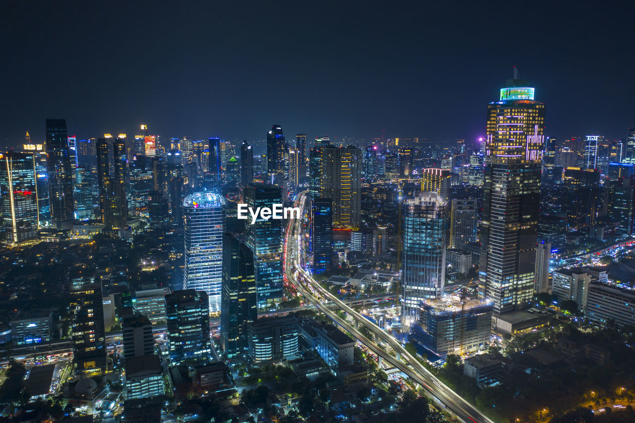 HIGH ANGLE VIEW OF ILLUMINATED BUILDINGS AGAINST SKY AT NIGHT