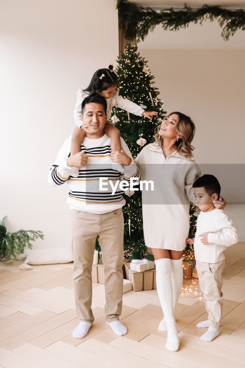 An asian multi-racial family with two children celebrate the christmas in a decorated indoor house