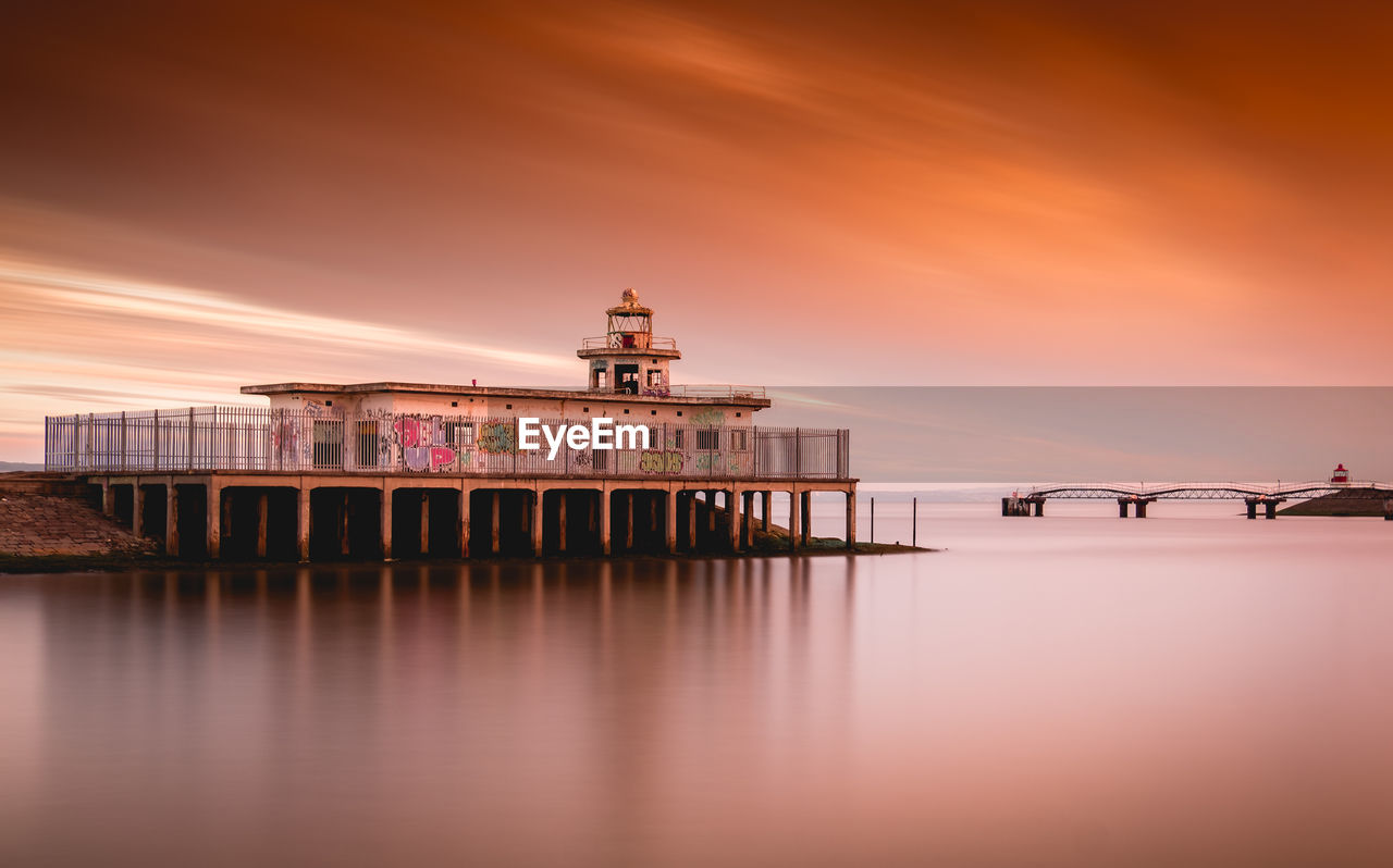 Pier over sea against sky during sunset