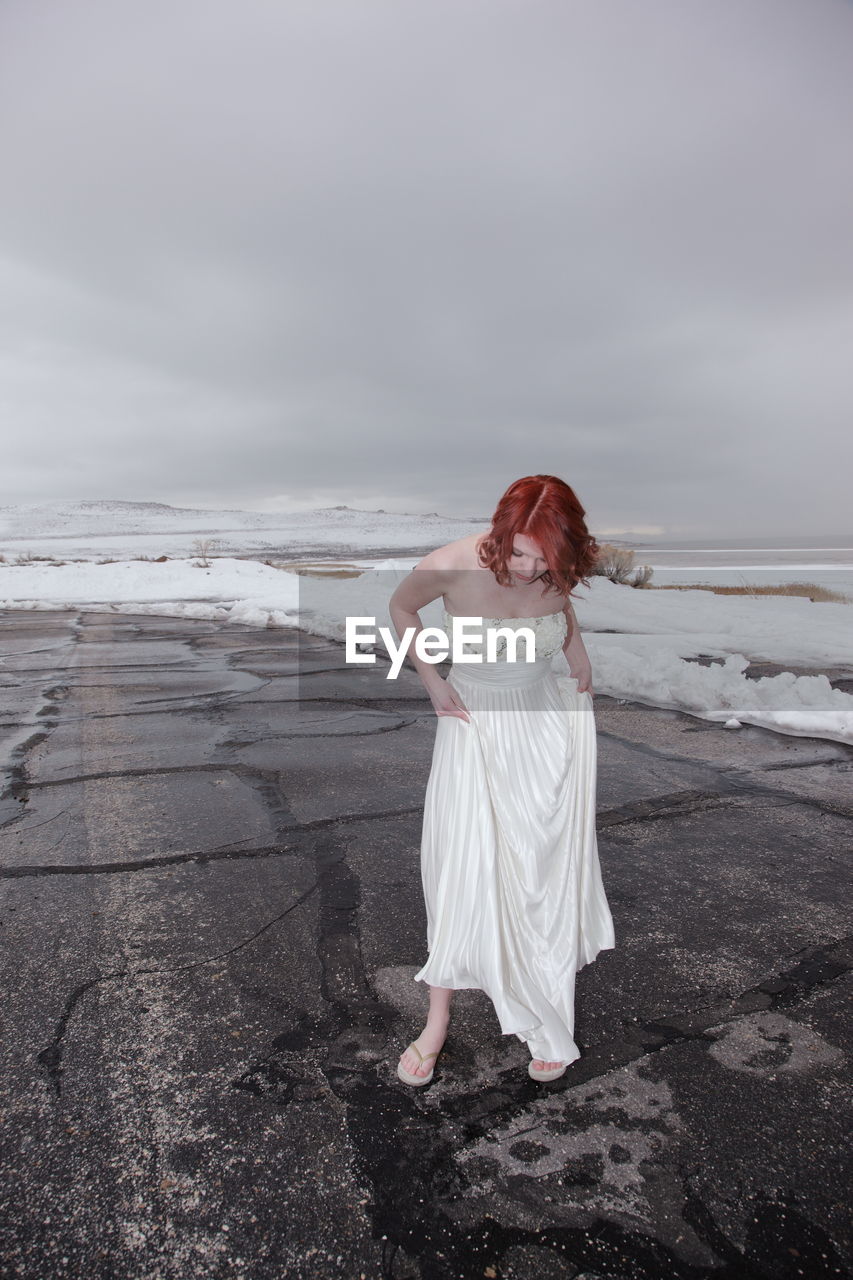 Full length of young woman standing on frozen shore