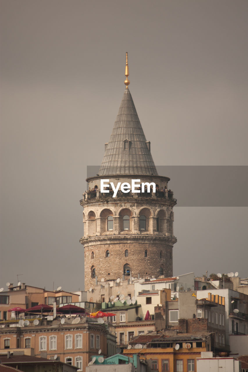 Low angle view of galata tower amidst buildings against clear sky