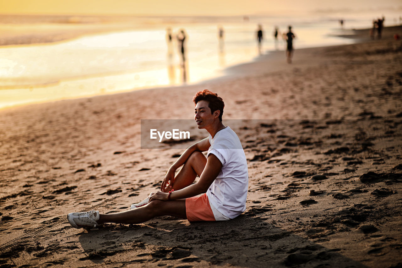 Side view of man sitting on beach