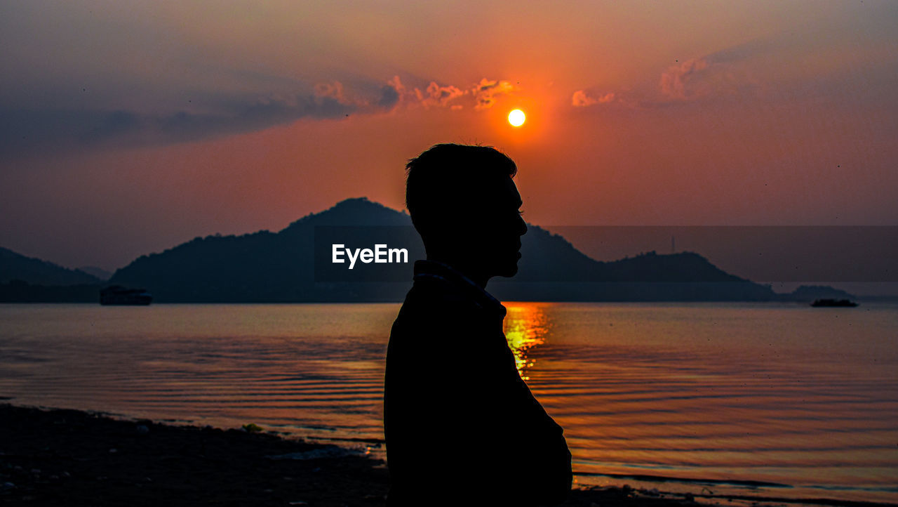 SILHOUETTE WOMAN LOOKING AT SEA DURING SUNSET