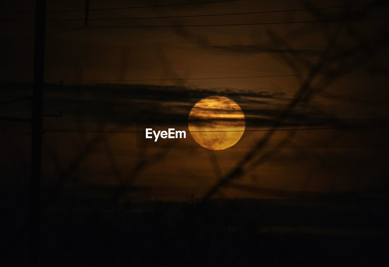 Close-up of moon over silhouette landscape against sky