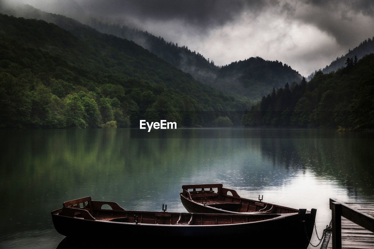 Boats moored in lake against mountains