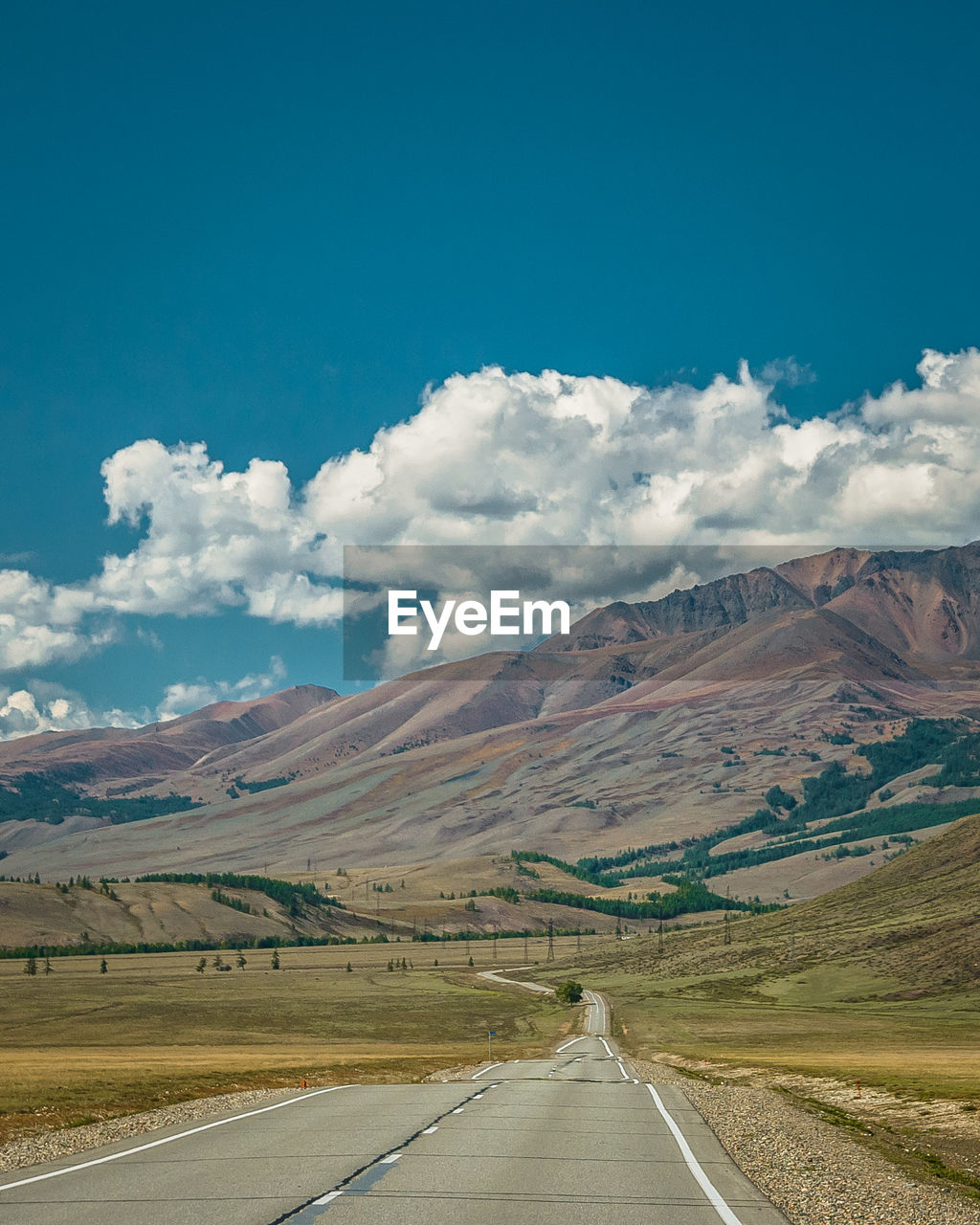 Road leading towards mountains against sky