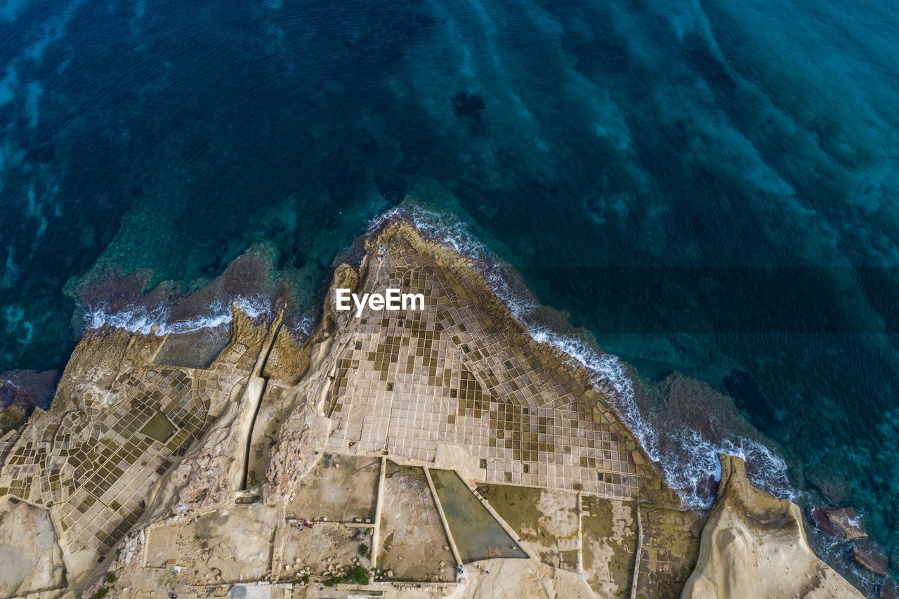 Aerial view at coastline of bahar ic-caghaq, malta with salt pans.