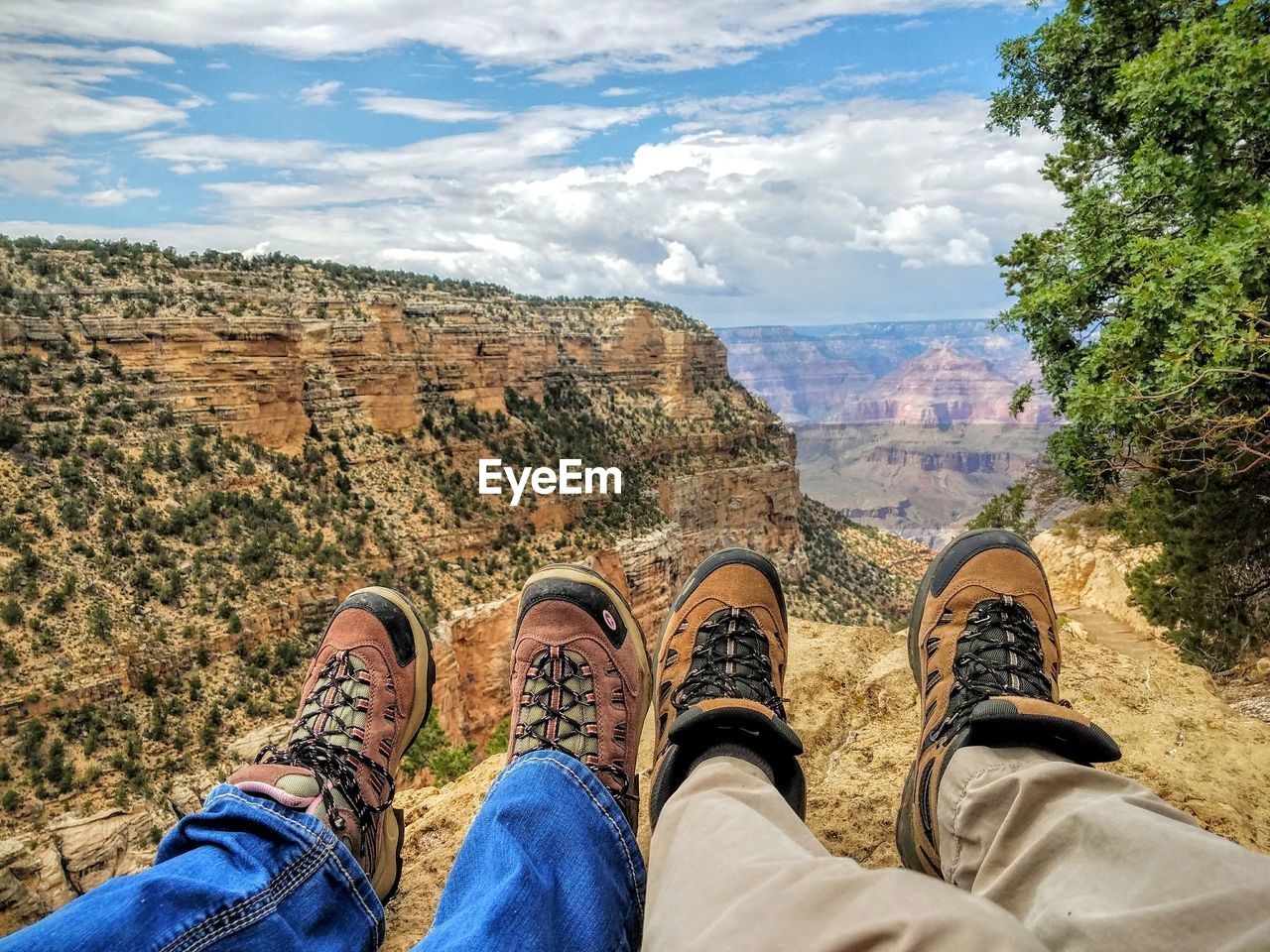 Low section of people relaxing at grand canyon national park against cloudy sky