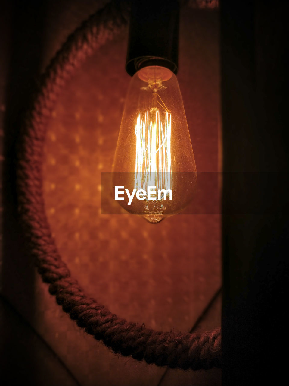 Low angle view of illuminated light bulb in darkroom