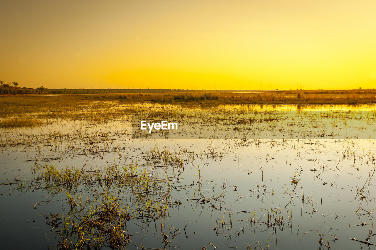 SCENIC VIEW OF LAKE AGAINST SKY AT SUNSET