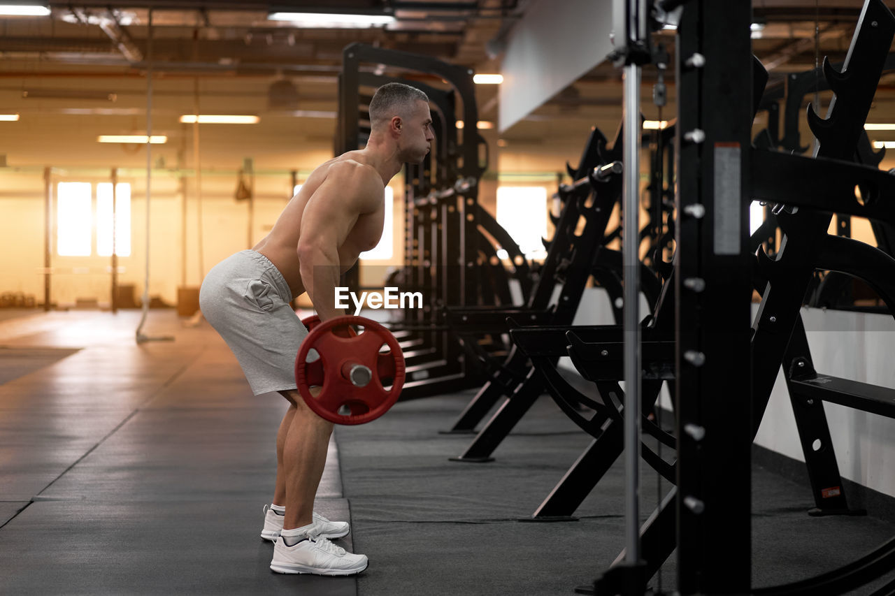 Full length side view of man exercising at gym