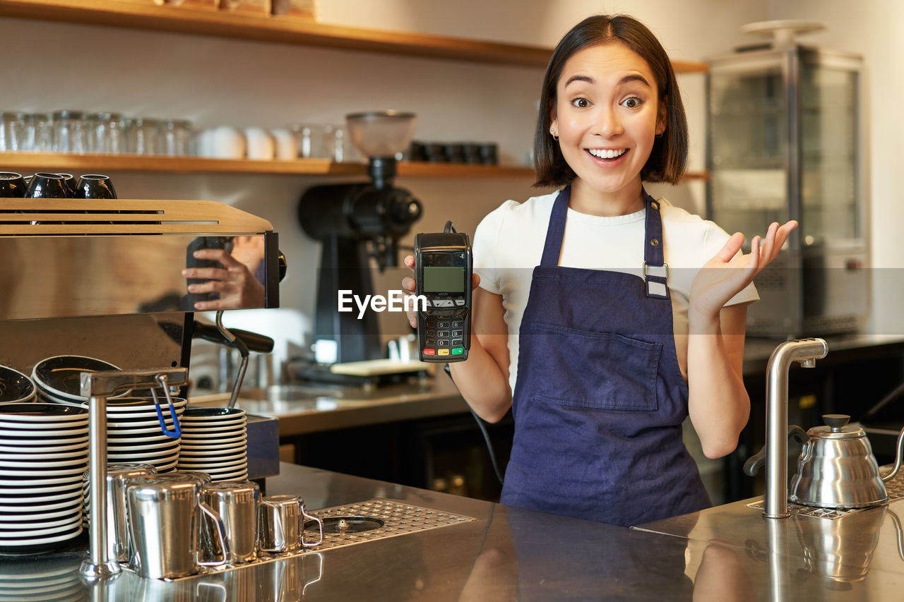 portrait of smiling young woman standing in cafe