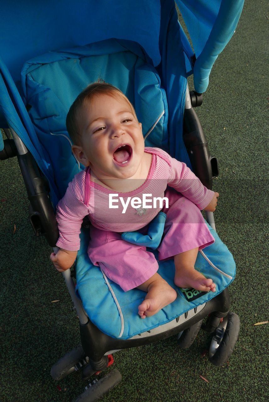 High angle view of baby screaming in stroller on field