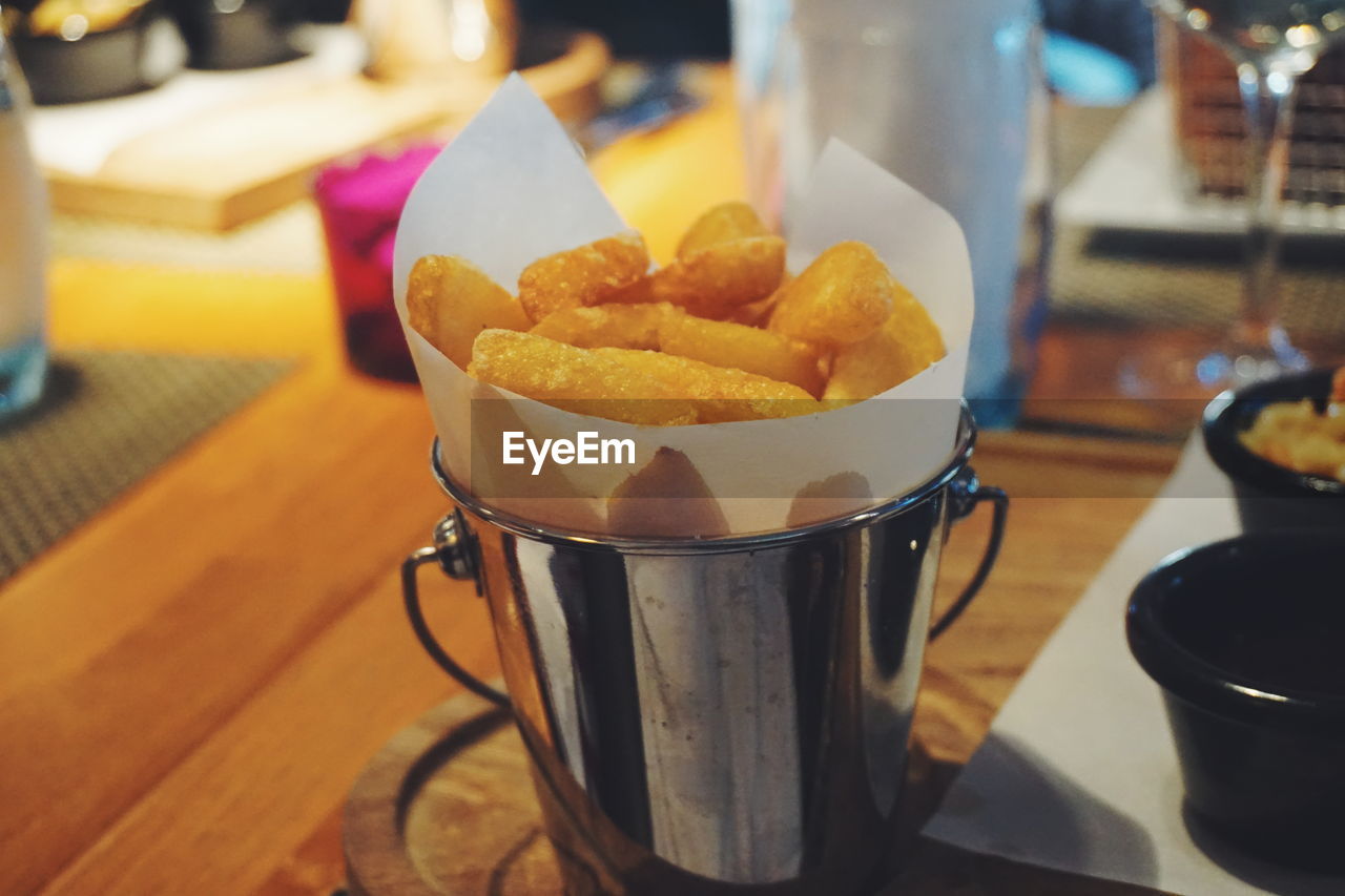 Close-up of french fries served in bucket on table