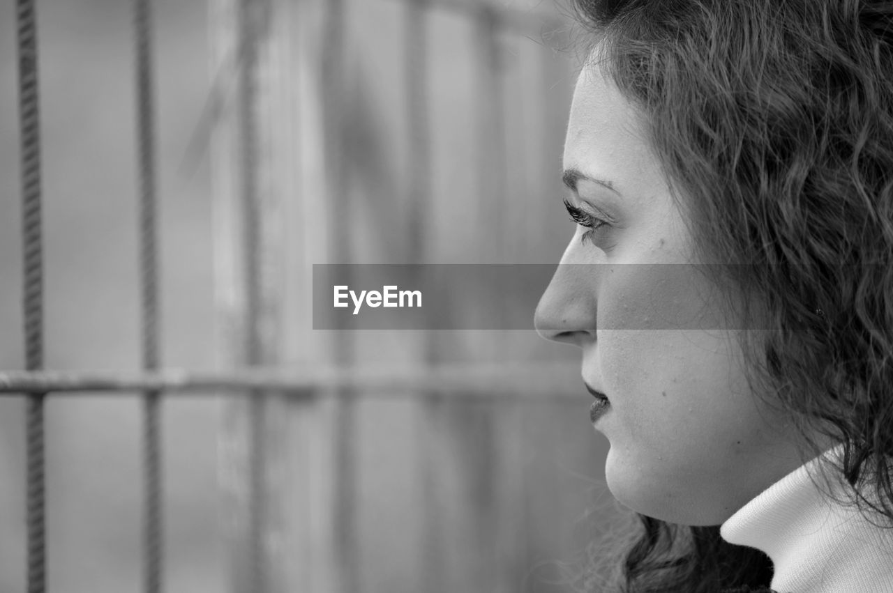 Close-up of young woman looking through a grate