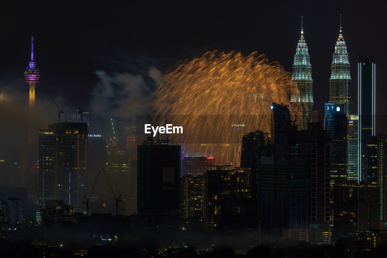 Firework display over illuminated buildings in city at night