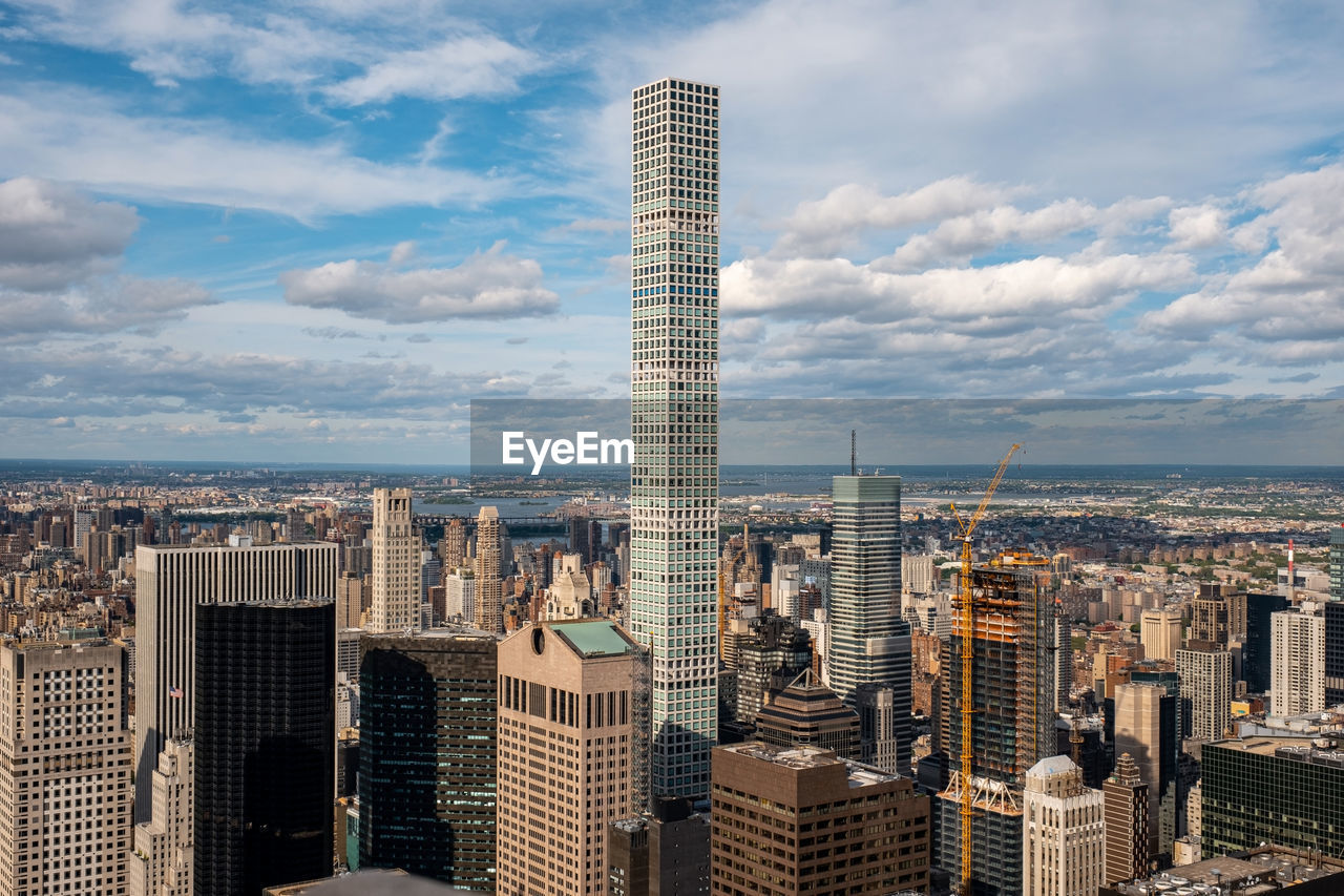 Aerial view of buildings in city against cloudy sky