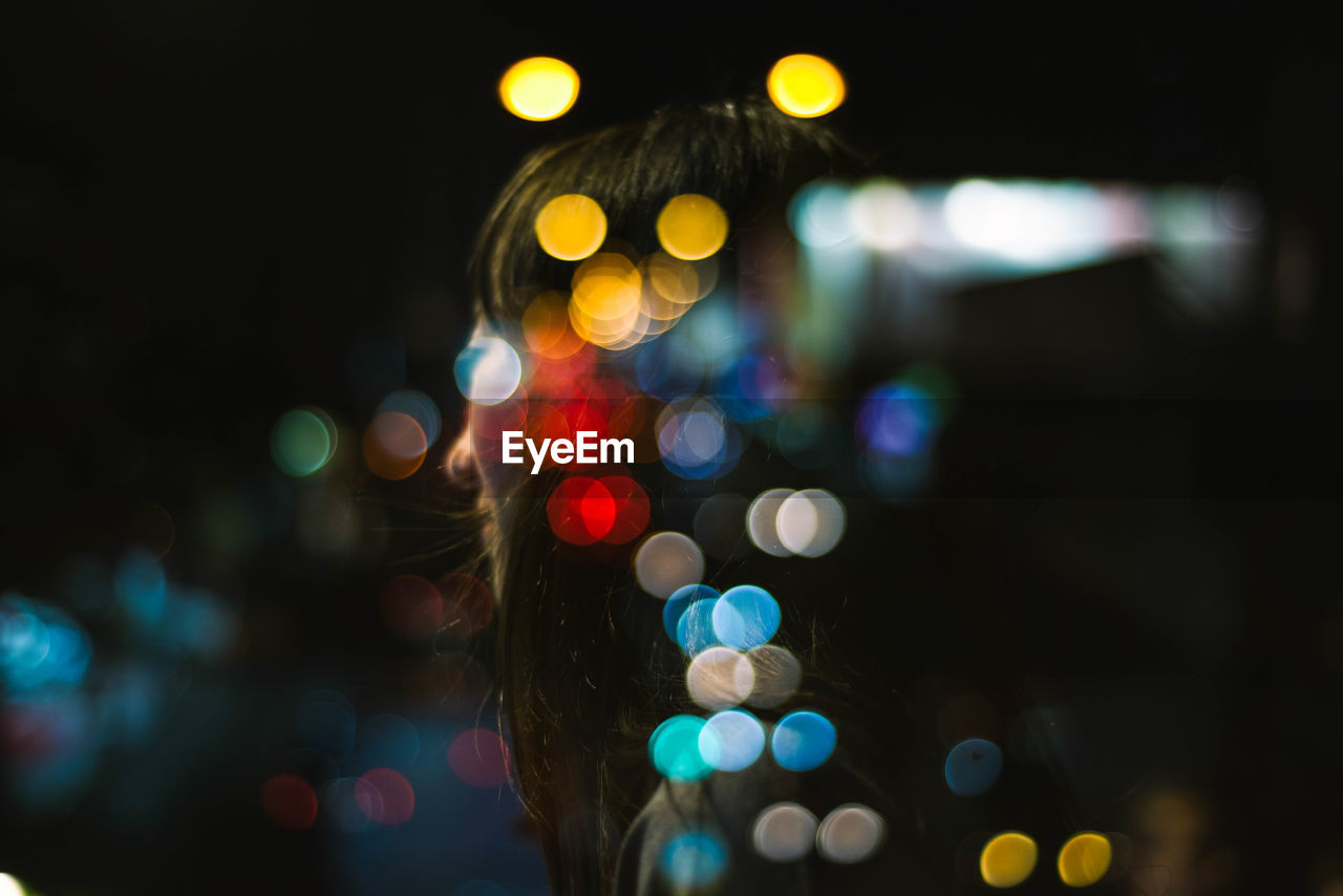 Defocused image of lights with a girl looking for the future, double exposure