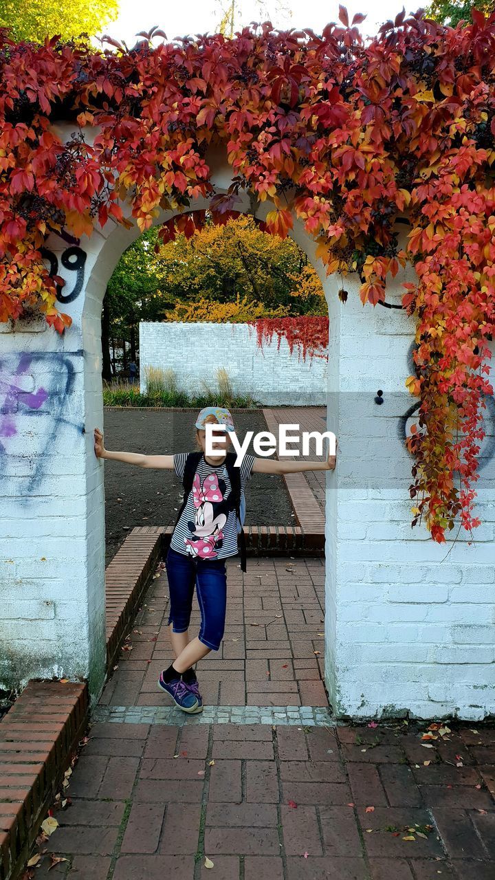 Portrait of smiling girl standing at entrance during autumn