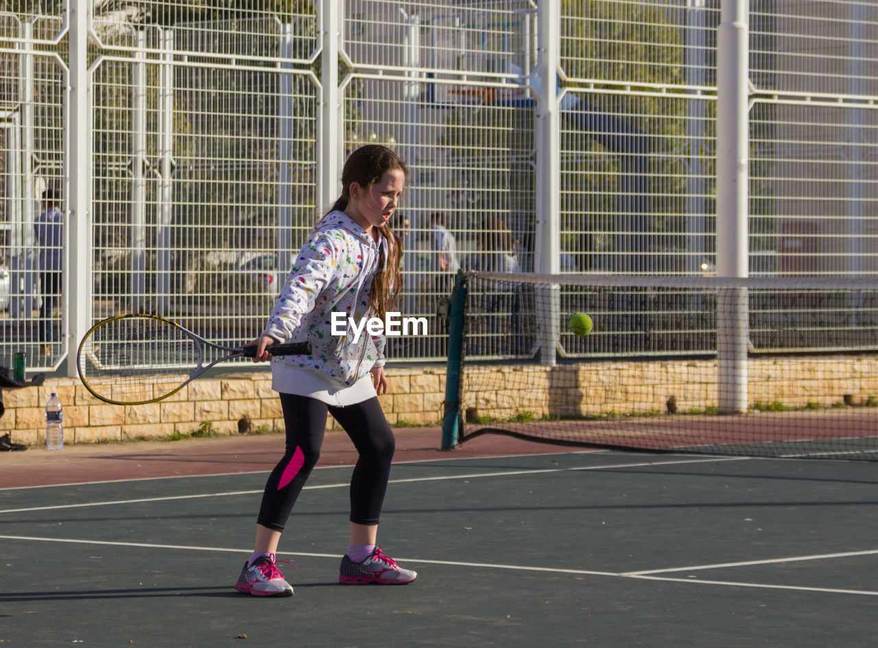 Full length of girl playing tennis in court