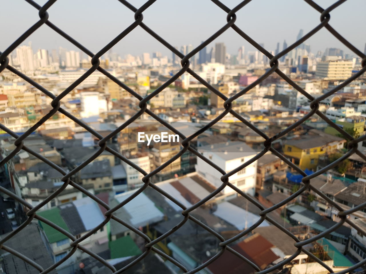 Close-up of cityscape seen through chainlink fence