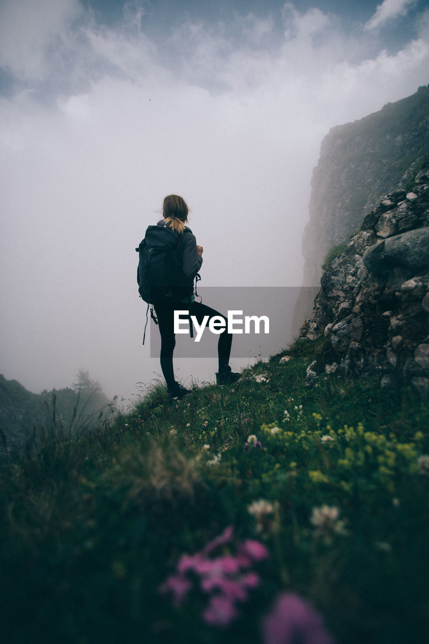 LOW ANGLE VIEW OF MAN WALKING ON MOUNTAIN