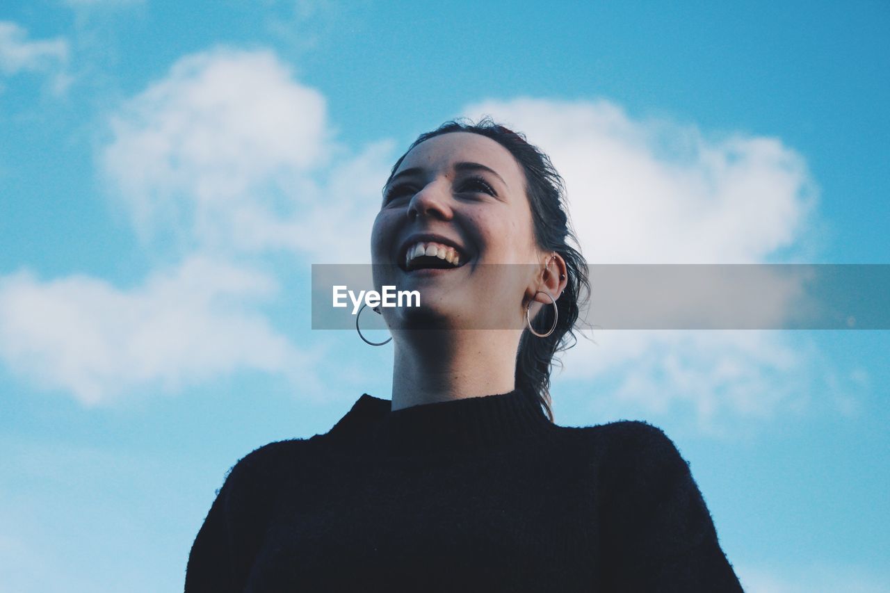 LOW ANGLE VIEW OF WOMAN STANDING AGAINST SKY