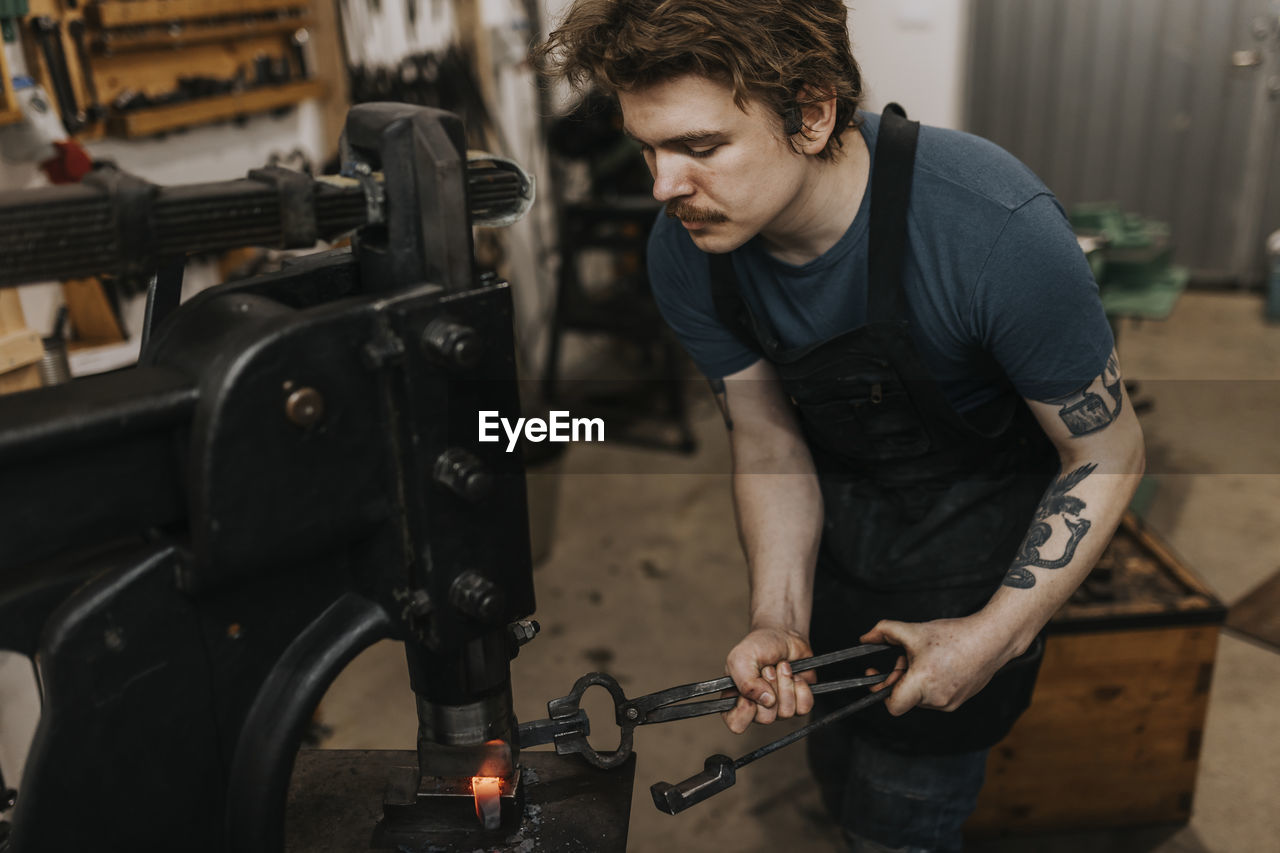 Male blacksmith forging metal in workshop