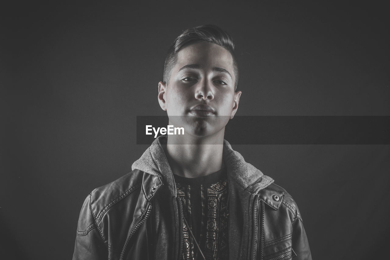 Portrait of young man against black background