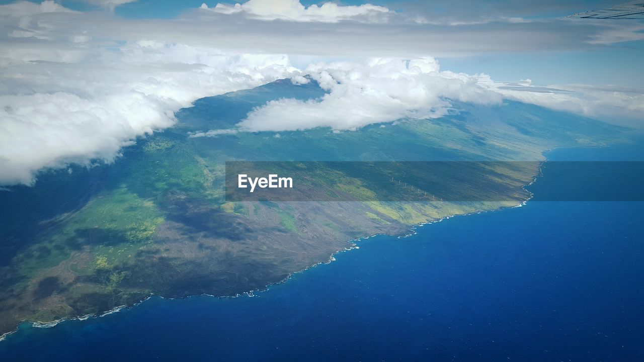 Aerial view of sea and mountains against cloudy sky