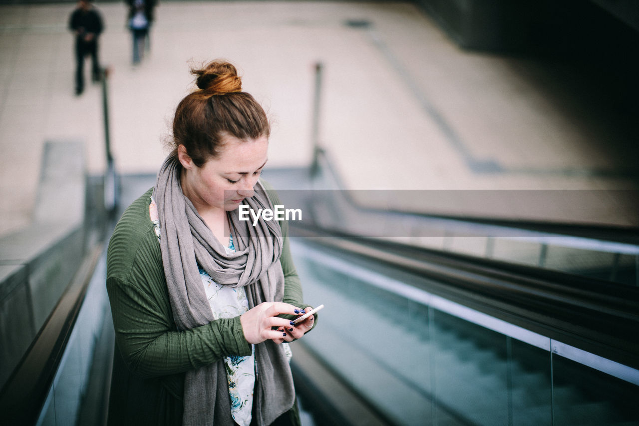 YOUNG WOMAN USING PHONE ON RAILROAD STATION