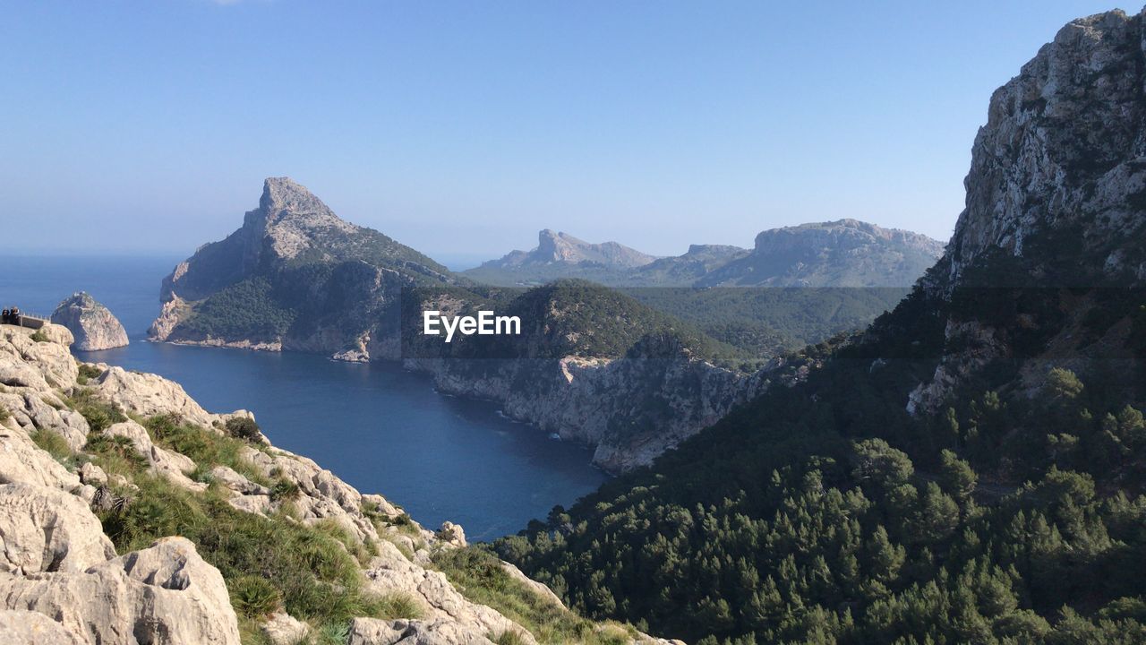 Scenic view of sea and mountains against clear sky