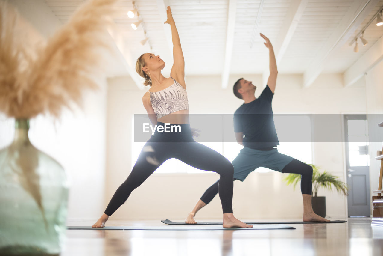 A couple in reverse warrior pose during yoga.