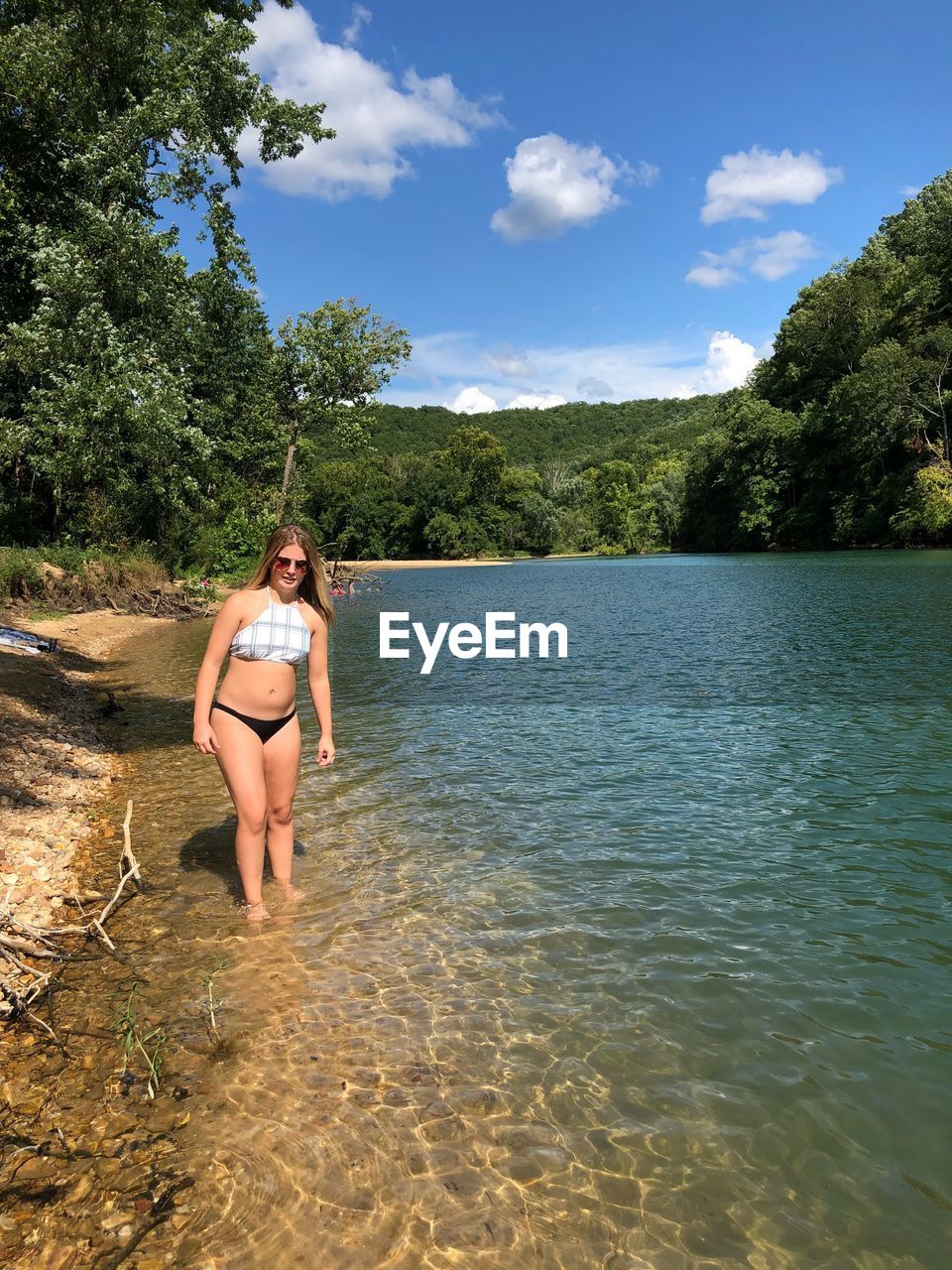 Portrait of teenage girl in bikini standing at lake