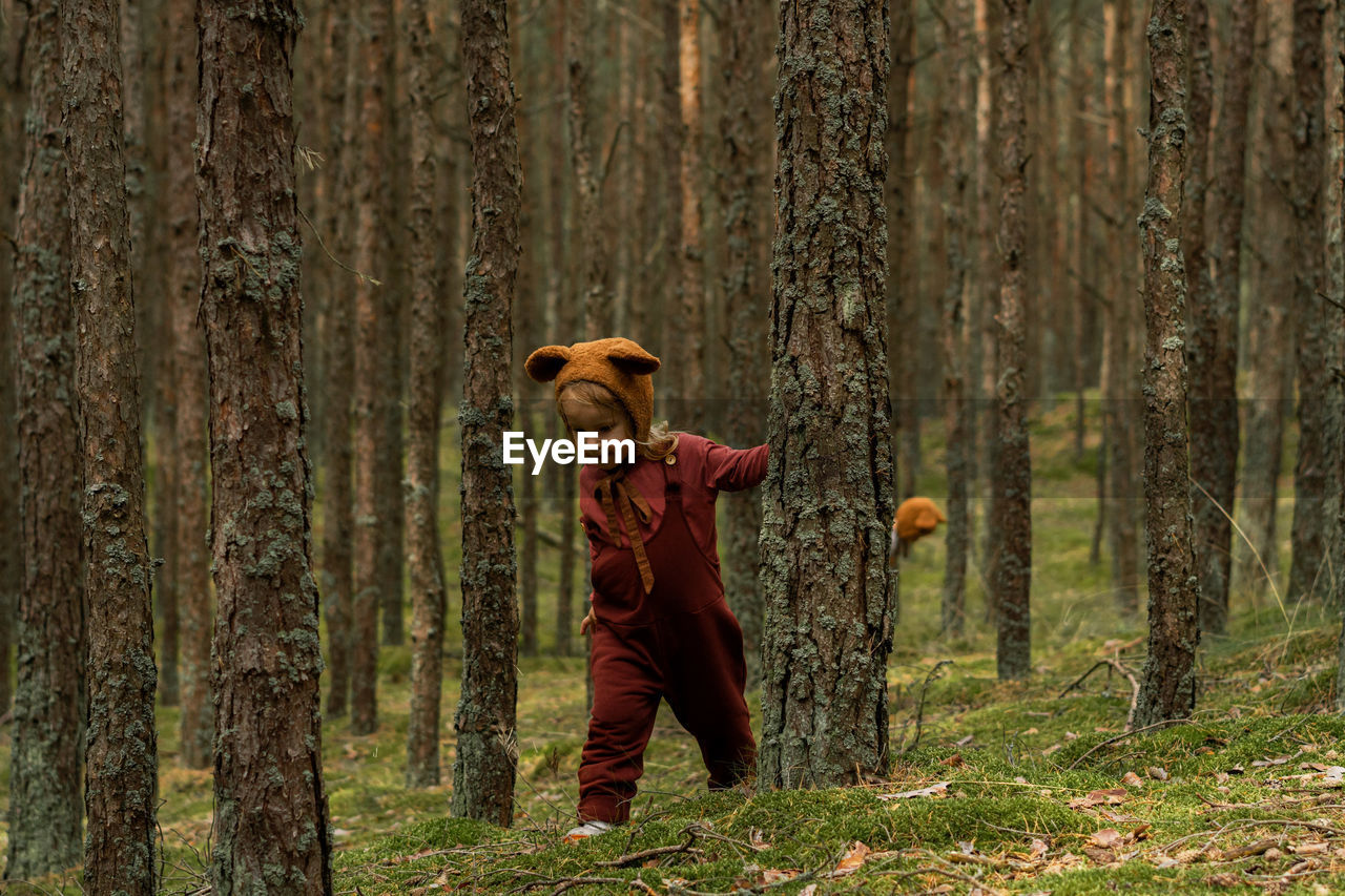 Toddler baby girl in bear bonnet walking in the woods