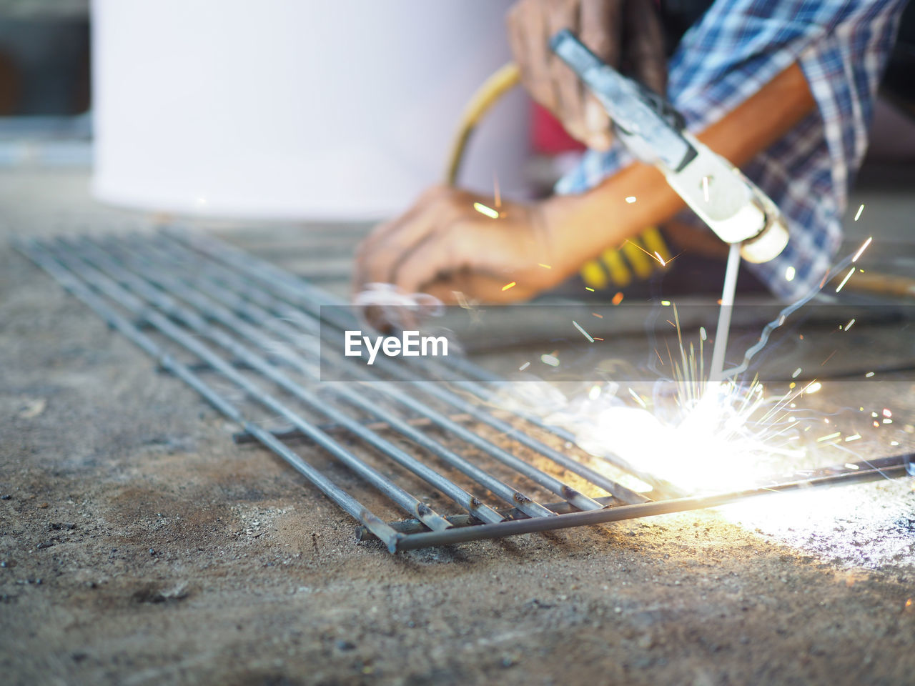 Cropped hands of welder welding metal in workshop