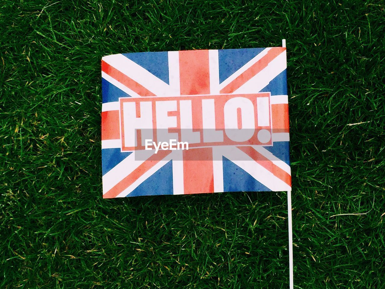 Directly above shot of british flag with hello sign on grassy field