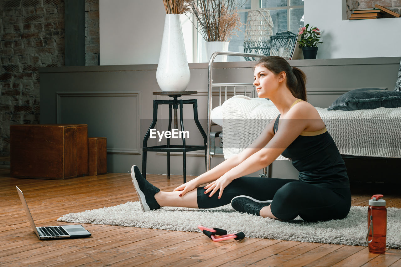 The athlete stretching , meditating, sitting on a floor in the bedroom