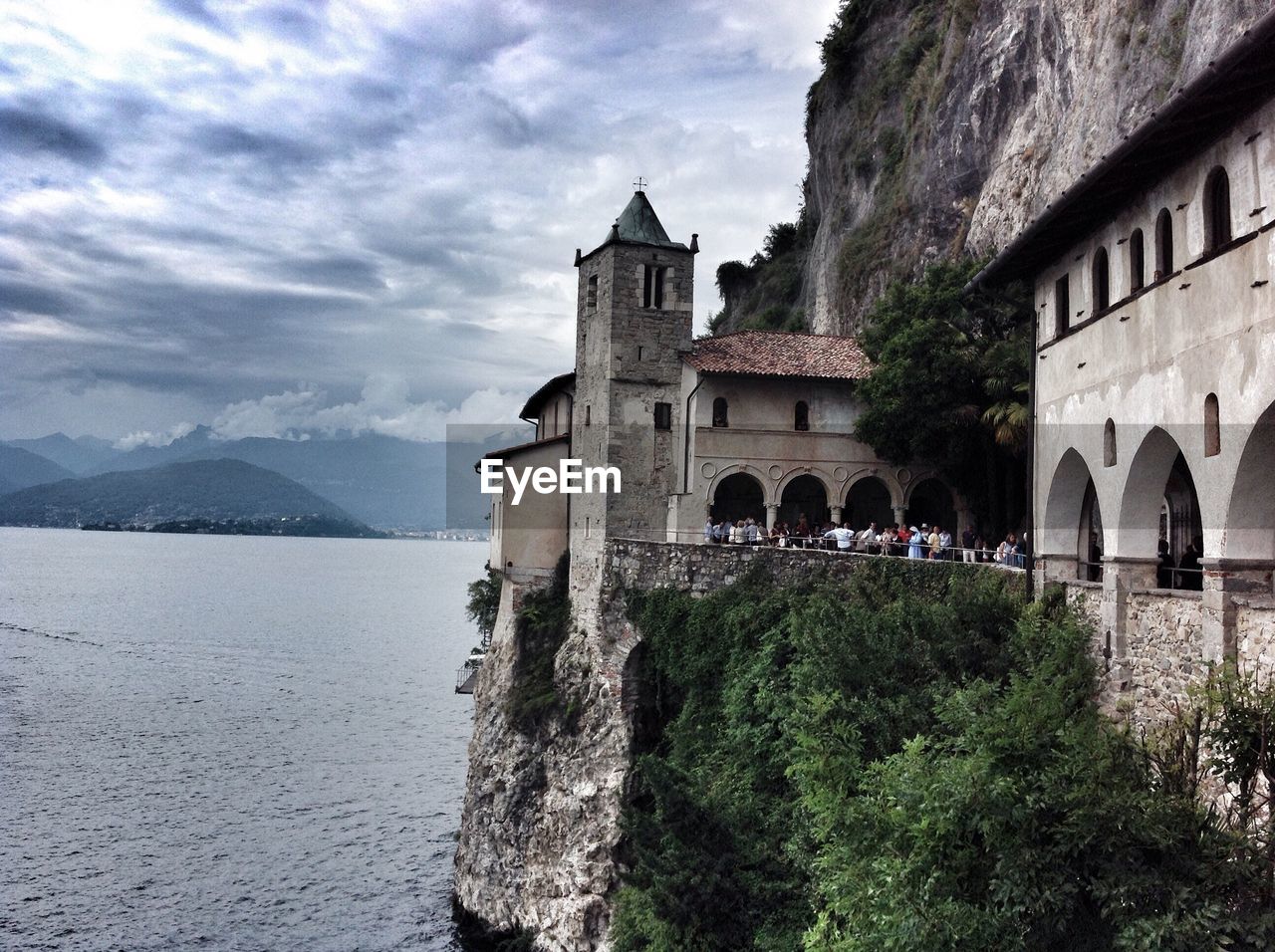 BUILT STRUCTURE BY TREES AND MOUNTAINS AGAINST SKY