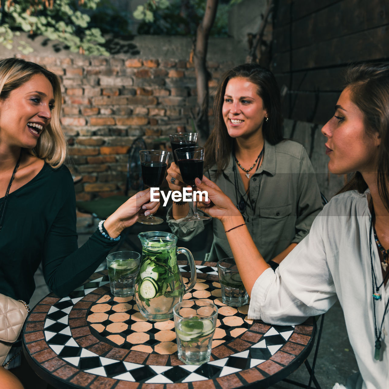 Female friends toasting wineglasses at outdoors restaurant during night