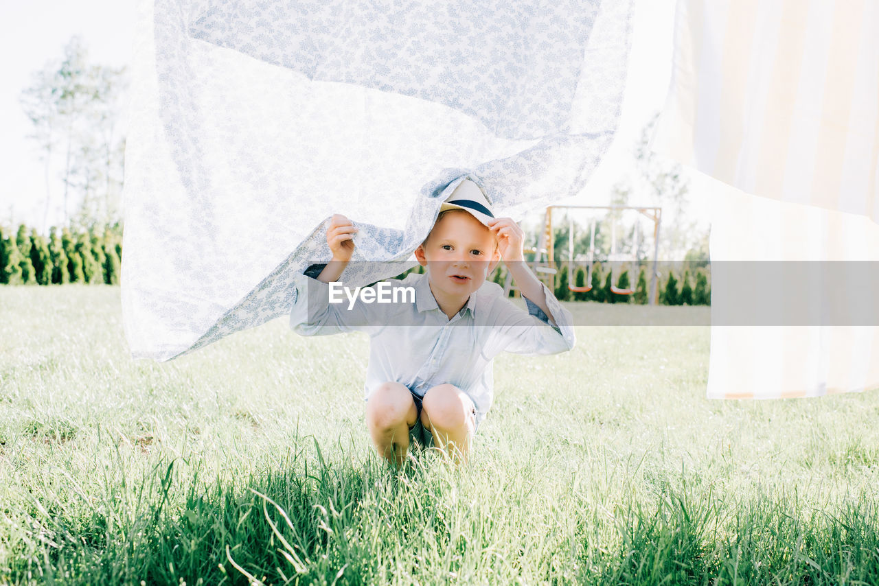 Young boy peeking through the washing on the line playfully at home