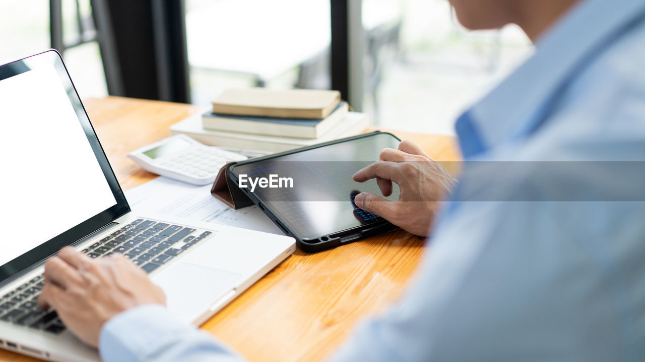 Midsection of man using laptop on table